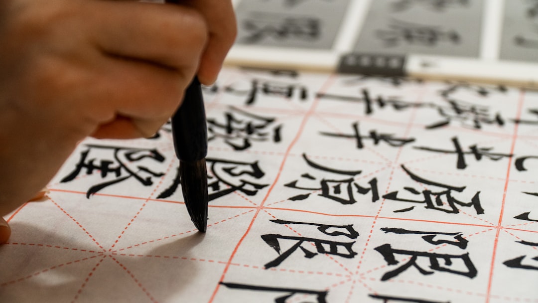 Student practising Chinese characters on grid practice paper with a brush pen